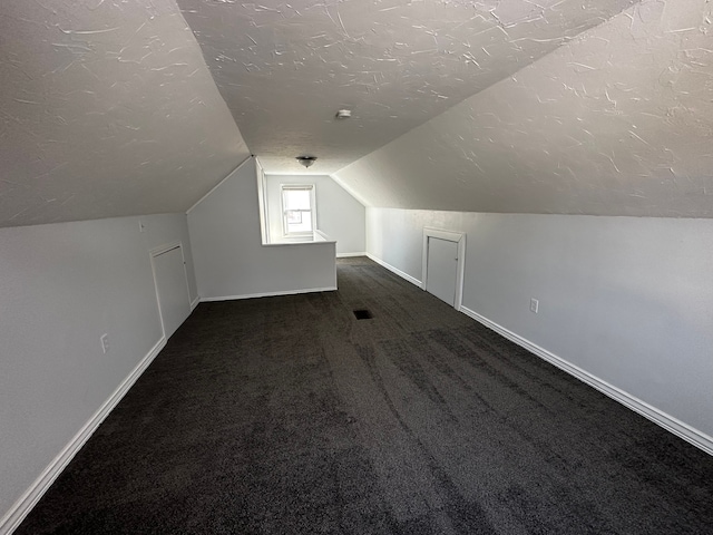 additional living space featuring baseboards, carpet floors, a textured ceiling, and vaulted ceiling