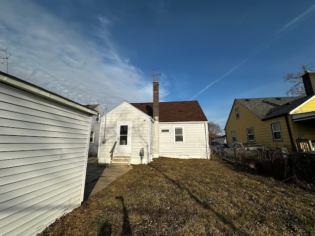 rear view of house featuring fence, a chimney, and entry steps