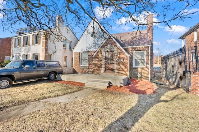 view of front facade featuring brick siding, board and batten siding, a chimney, and fence