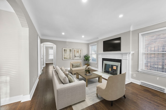 living area featuring visible vents, recessed lighting, wood finished floors, arched walkways, and a glass covered fireplace