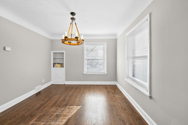 unfurnished dining area featuring an inviting chandelier, visible vents, baseboards, and dark wood-type flooring