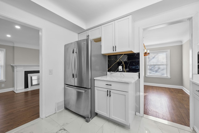 kitchen with visible vents, freestanding refrigerator, decorative backsplash, white cabinets, and marble finish floor