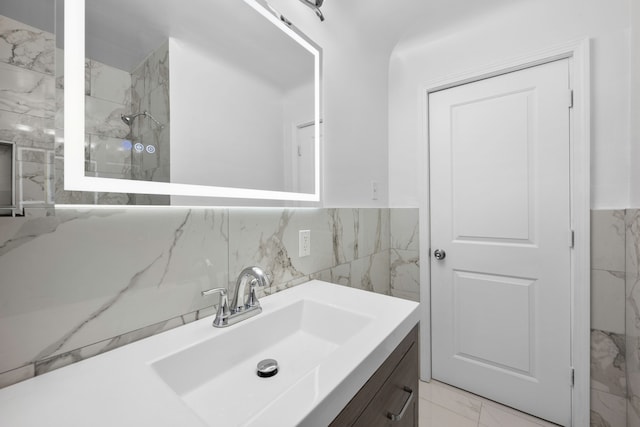 bathroom with vanity, tile walls, a shower, and marble finish floor