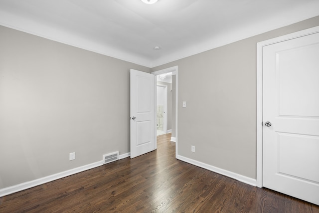 unfurnished bedroom featuring visible vents, dark wood-style floors, and baseboards