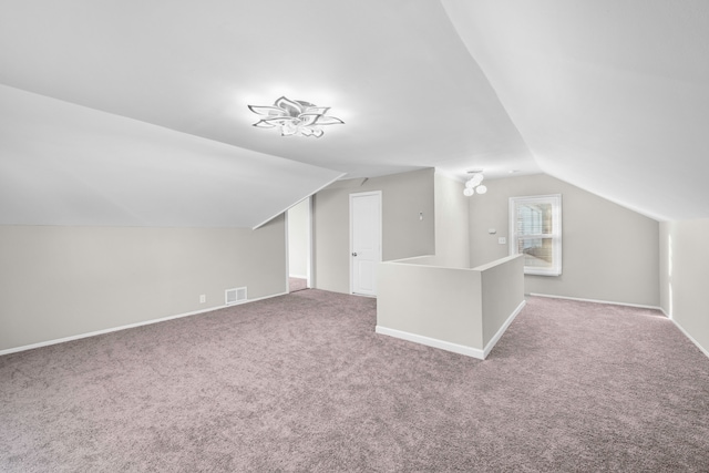 additional living space featuring visible vents, carpet flooring, baseboards, and lofted ceiling