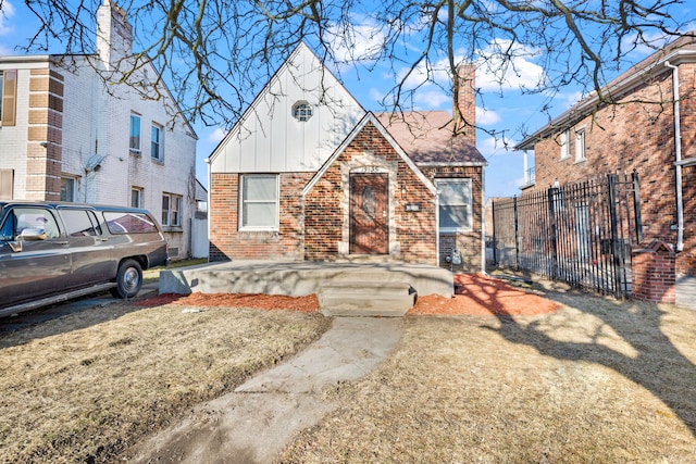 tudor home featuring brick siding, fence, board and batten siding, and a chimney