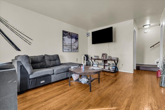 living area featuring baseboards, wood finished floors, and stairs