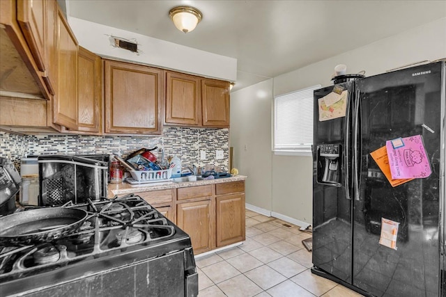 kitchen featuring light tile patterned floors, a sink, black appliances, light countertops, and tasteful backsplash