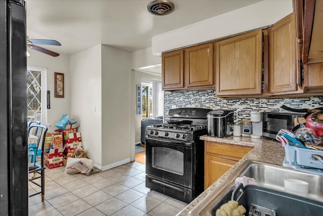 kitchen featuring light tile patterned floors, a ceiling fan, light countertops, black gas range, and tasteful backsplash