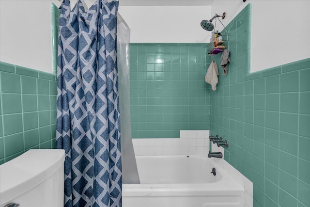 full bathroom with a wainscoted wall, toilet, tile walls, and shower / bath combo