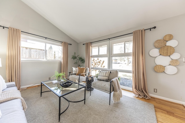 living room with light wood-style flooring, baseboards, and vaulted ceiling