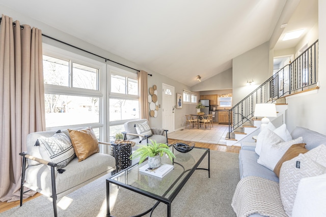 living area featuring stairway, light wood finished floors, and high vaulted ceiling