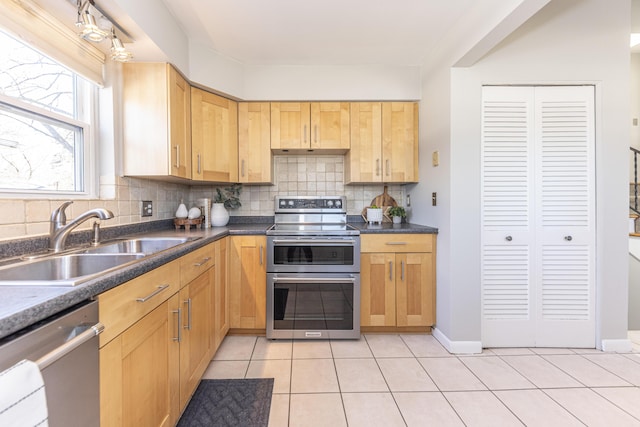 kitchen featuring a sink, decorative backsplash, appliances with stainless steel finishes, and light tile patterned flooring