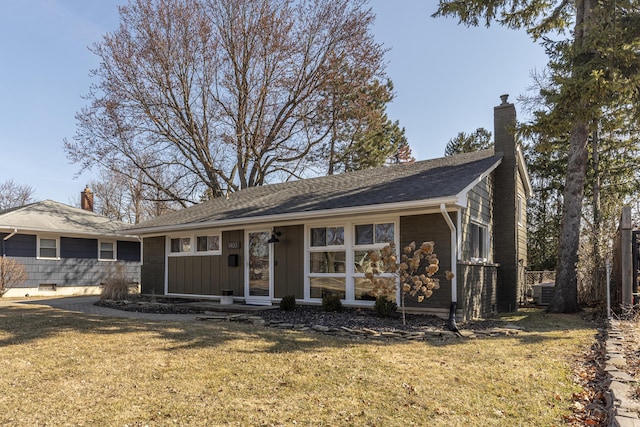 ranch-style house featuring central air condition unit, roof with shingles, a chimney, and a front lawn