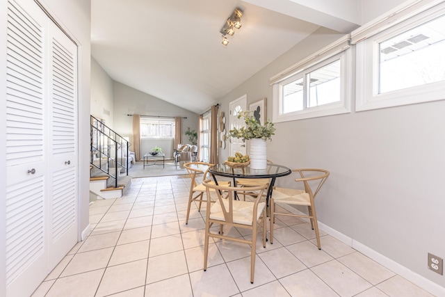 dining space featuring stairs, vaulted ceiling, light tile patterned floors, and baseboards