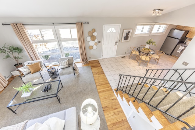 living room with stairway, visible vents, baseboards, and wood finished floors