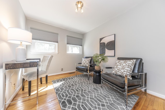 living area featuring visible vents, baseboards, and hardwood / wood-style flooring