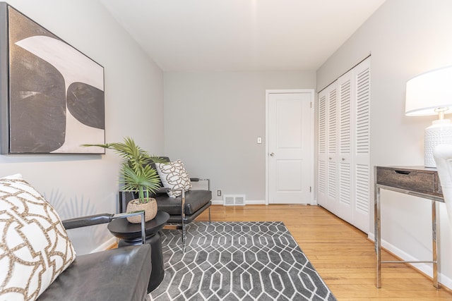 living area with visible vents, light wood-style flooring, and baseboards