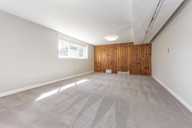 unfurnished room featuring visible vents, carpet floors, wooden walls, and baseboards