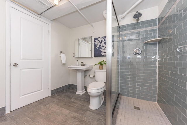 full bath featuring toilet, wood finished floors, baseboards, and tiled shower