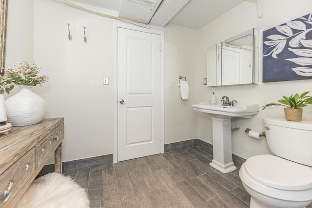 bathroom featuring toilet, wood finished floors, baseboards, and a sink