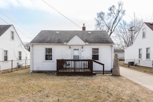 rear view of property featuring a shingled roof, fence, central AC unit, a lawn, and a chimney