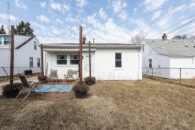 back of property with a lawn and fence