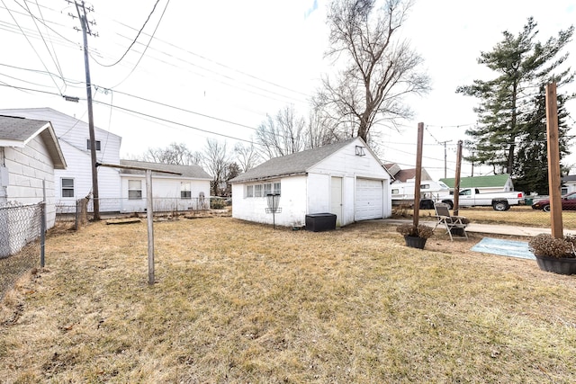 view of yard with a detached garage, an outbuilding, and fence