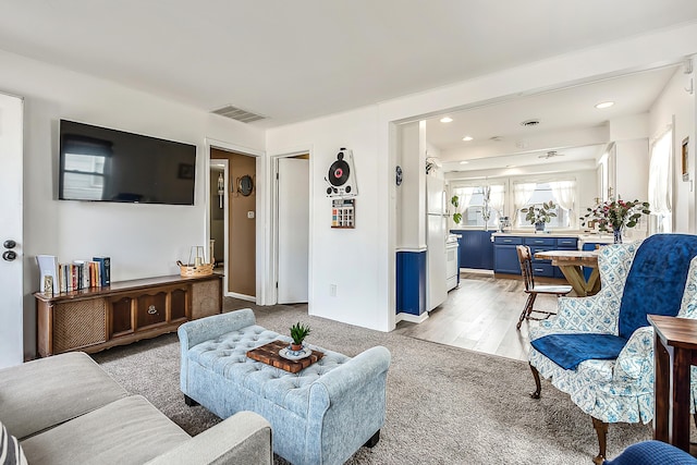 living room with recessed lighting, visible vents, and light carpet