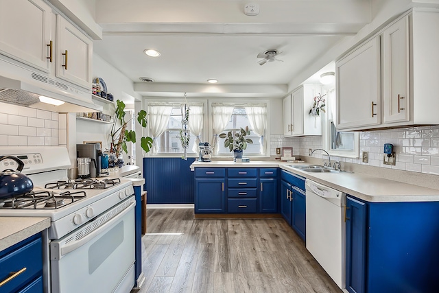 kitchen with white appliances, blue cabinets, light wood finished floors, and a sink