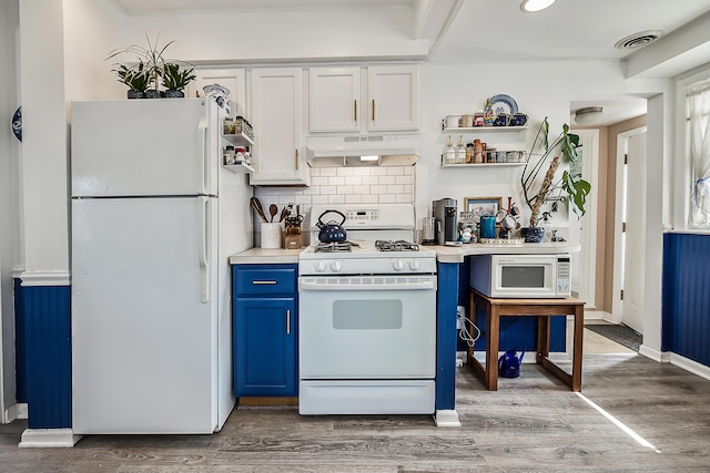 kitchen with visible vents, under cabinet range hood, wood finished floors, white appliances, and blue cabinets