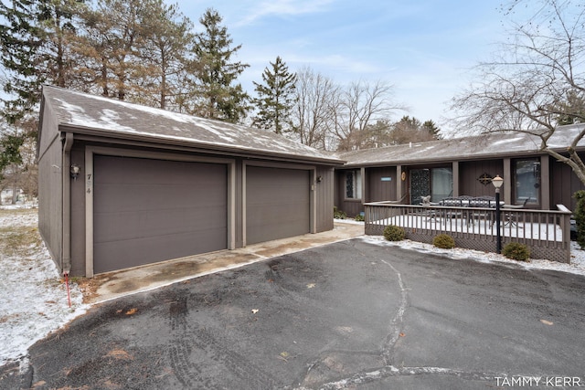 view of front of property featuring aphalt driveway, an attached garage, and an outbuilding