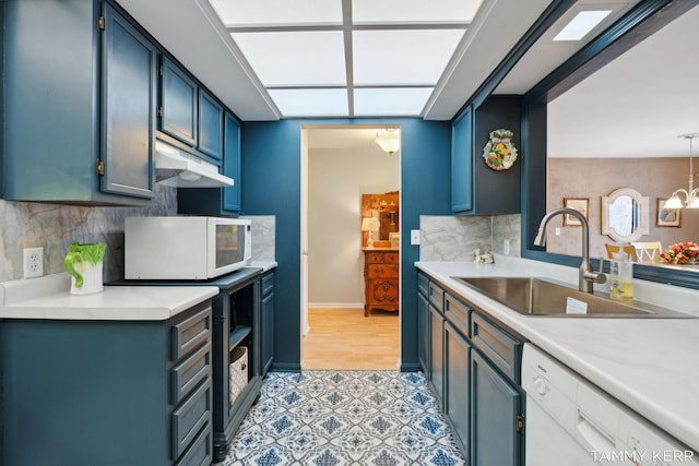 kitchen featuring under cabinet range hood, white appliances, light countertops, and a sink