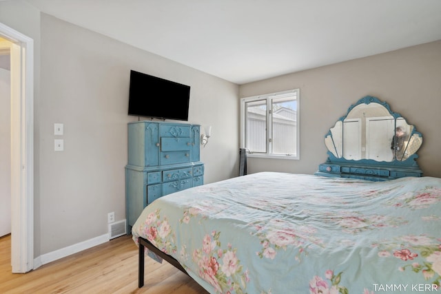 bedroom with visible vents, wood finished floors, and baseboards