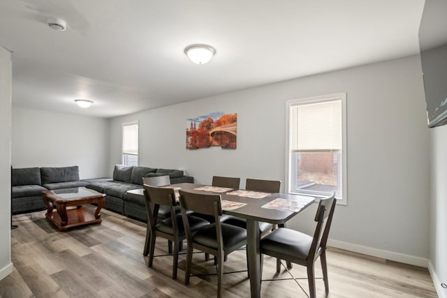 dining space featuring light wood-style flooring, plenty of natural light, and baseboards