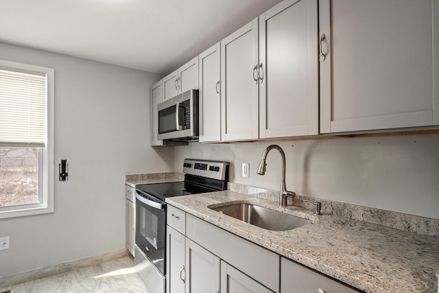 kitchen featuring baseboards, light stone countertops, marble finish floor, stainless steel appliances, and a sink