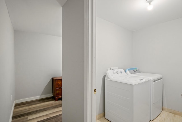 washroom with laundry area, wood finished floors, separate washer and dryer, and baseboards