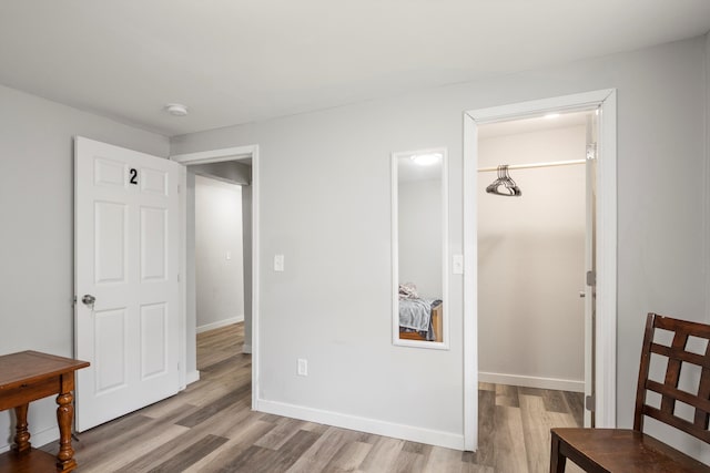 bedroom with a closet, baseboards, wood finished floors, and a spacious closet