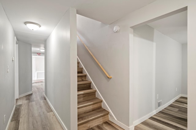 staircase with visible vents, wood finished floors, and baseboards