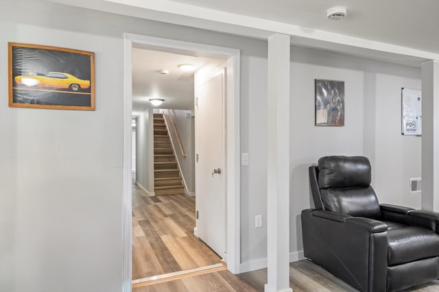 sitting room featuring stairway, baseboards, and light wood-style floors