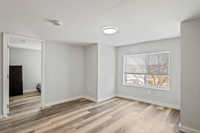 unfurnished room featuring baseboards and light wood finished floors