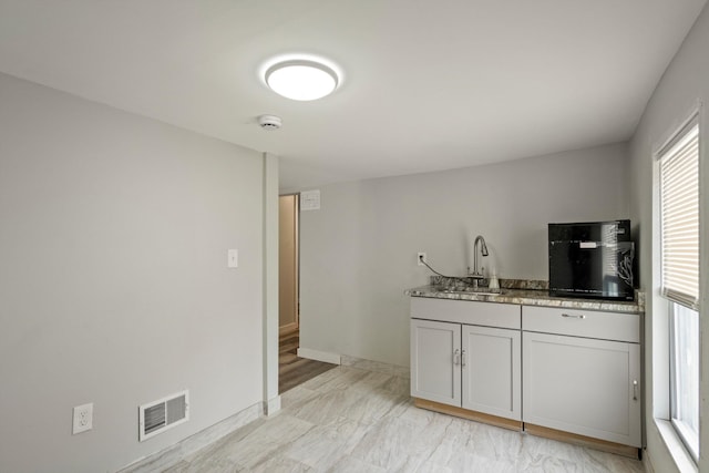 kitchen featuring baseboards, visible vents, and a sink