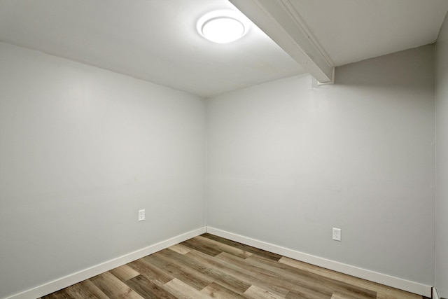 unfurnished room with light wood-type flooring, baseboards, and beam ceiling