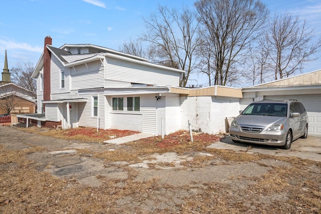 view of side of property with concrete driveway and a chimney