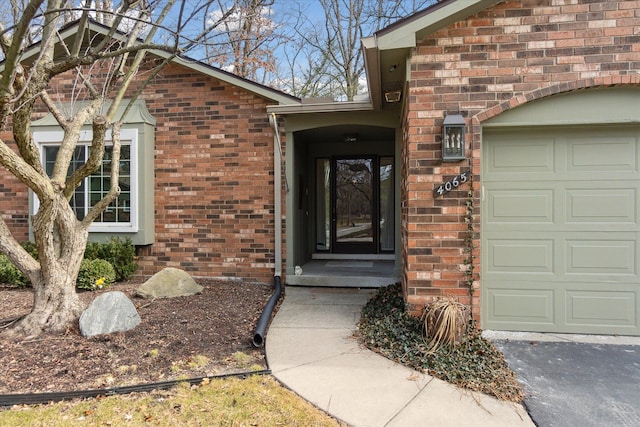 view of exterior entry with brick siding and a garage