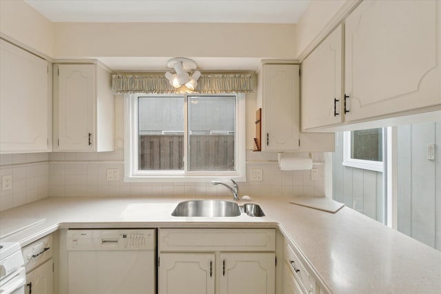 kitchen with a sink, backsplash, white cabinetry, white dishwasher, and light countertops