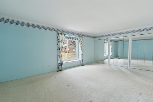 unfurnished bedroom with visible vents, carpet floors, and multiple closets