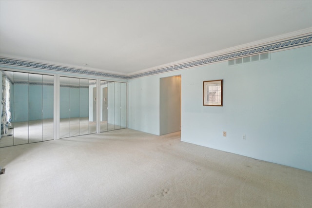 unfurnished bedroom with crown molding, carpet flooring, visible vents, and multiple closets