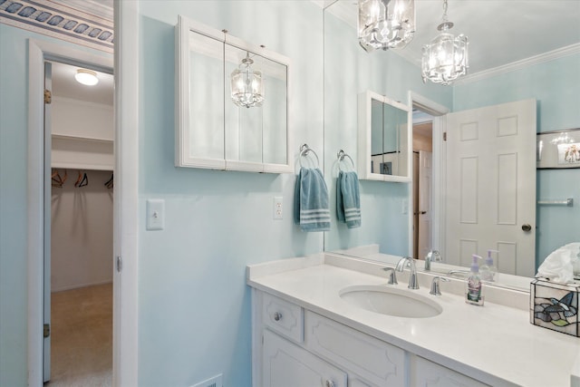 bathroom featuring vanity, a spacious closet, a chandelier, and ornamental molding