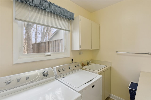 laundry area featuring cabinet space, washing machine and dryer, baseboards, and a sink